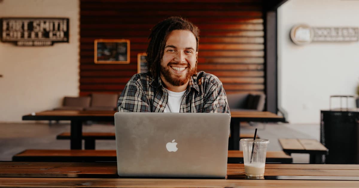 Smiling small business owner working on a laptop in a cafe