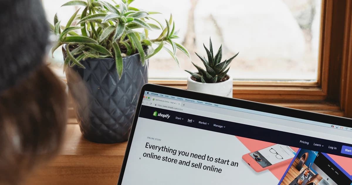 Person browsing an e-commerce platform website on a laptop to start an online store