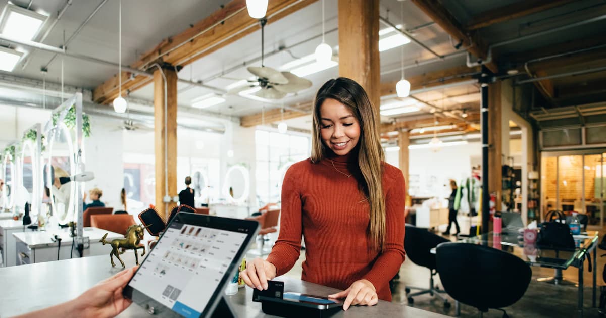 Smiling small business owner serving a customer at a modern shop counter